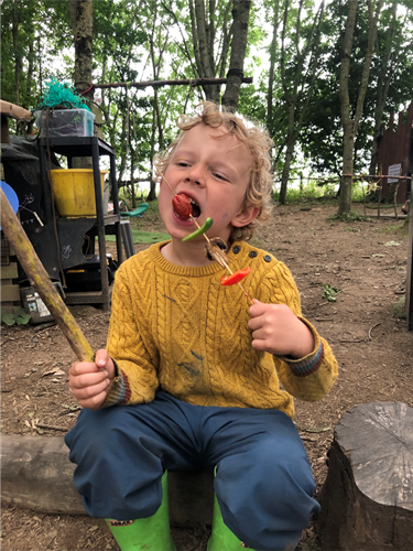 Child eating a vegetable kebab at forest school